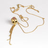 Polly Wales Forbidden Skull Necklace in 18k yellow recycled gold with pink fuchsia sapphires on an extra (XL) long chain forms this pendant necklace on white background.