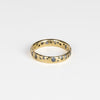 The Cornflower Blue Sapphire Confetti Band designed by Polly Wales is a narrow 18k yellow recycled gold wedding band/ring with speckled ombre light blue sapphires around the circumference. It is cast not set and handmade in Los Angeles.