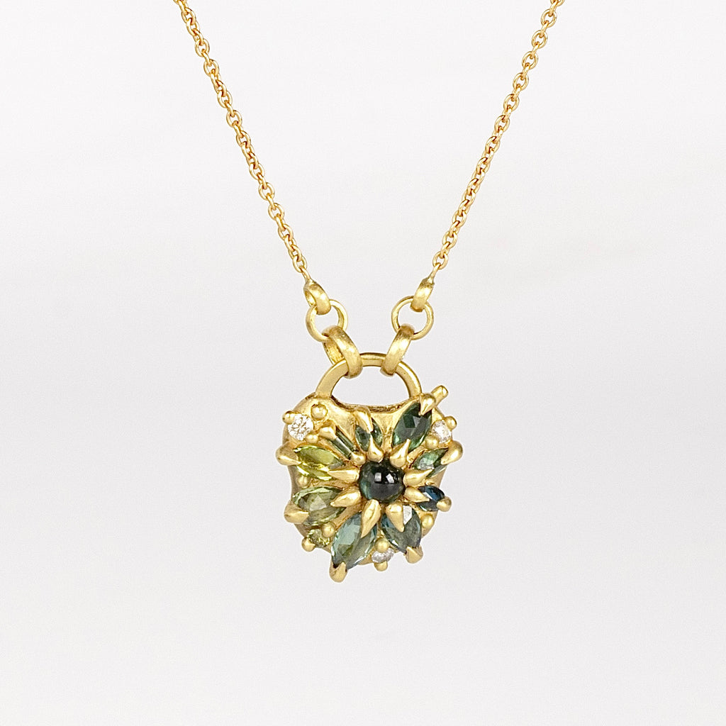 Green Fantaisie Encrusted Padlock Necklace by Polly Wales is a padlock in 18K yellow gold and encrusted with mixed green sapphires, a center cabochon and an accent diamond hanging on a chain that attaches to the lock handle by pulling the lever. Recycled gold. Cast in Place. Cast not set. Handmade in Los Angeles.