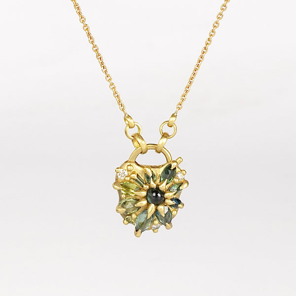 Green Fantaisie Encrusted Padlock Necklace by Polly Wales is a padlock in 18K yellow gold and encrusted with mixed green sapphires, a center cabochon and an accent diamond hanging on a chain that attaches to the lock handle by pulling the lever. Recycled gold. Cast in Place. Cast not set. Handmade in Los Angeles.