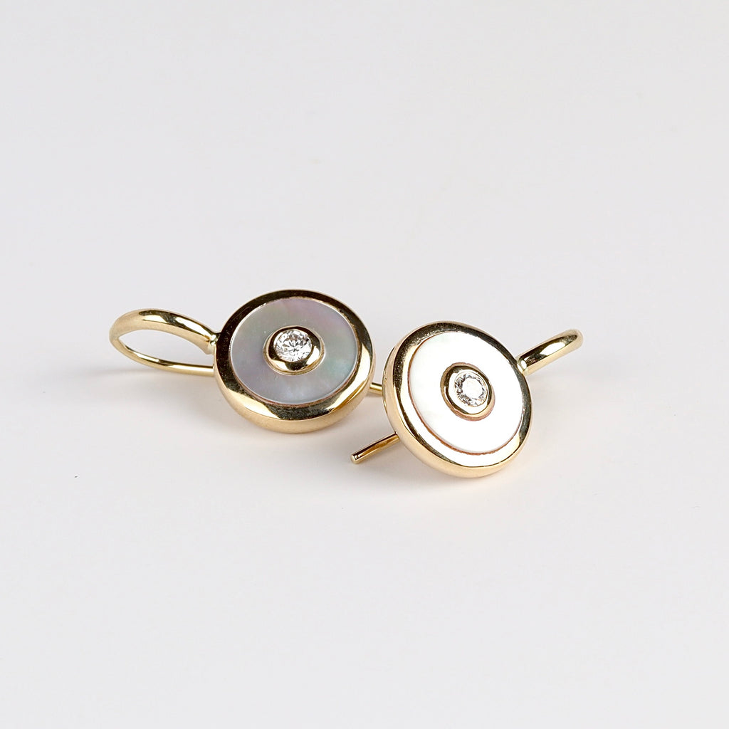 Midi Compass Hook Earrings in white Mother of Pearl by Retrouvai are round disc earrings with handcut stone inlay and a center diamond on a gold hook that hang close to the ear.