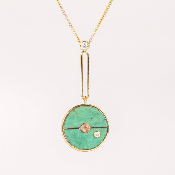 Compass Pendant in Green Turquoise and Lotus Garnet by Retrouvai is a unique modern take on an heirloom pendant. Stone inlay is accented with a center gem stone and white diamond. The compass hangs from an elongated paperclip link accented with a second white diamond. Handcrafted in Los Angeles.