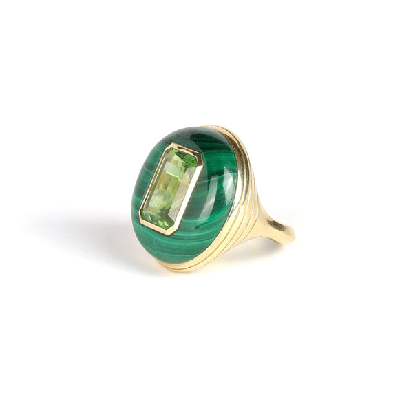 The Large Lollipop Ring in malachite and Green tourmaline by Retrouvai is a one of a kind signet ring featuring a chunky and rounded stone face with a translucent center stone set on a tiered edge and tapered band. This one is malachite with an emerald cut green tourmaline in the center. 