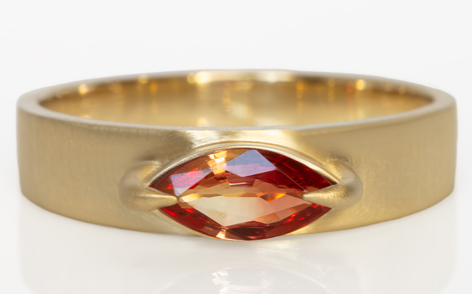 Studio shot on white of slim cigar band with sapphire.