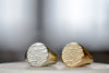 Tidal Round Signets by Fraser Hamilton known as the  'Tidal 11' is a round and solid modern signet ring in 9k yellow or white gold with polished band and matte face, featuring the maker's signature 'low tide' or 'ripple' texture on the face. 