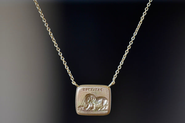 Lion and Mouse Duo Motto Necklace in 18k gold is a rectangular disc in gold with satin finish that will turn shiny over time features an image from the Aesop Fable ‘The Lion and the Mouse featuring the words 'patience". Made by stamping an 1800s carved seal with 'mottos' in French, Italian, Latin or English on to gold. 