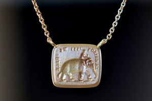 A rectangular disc in gold with satin finish that will turn shiny over time features an image of&nbsp;a man&nbsp;riding an elephant with the French motto "La raison fait ma force" (‘Reason is my strength.’) The elephant is a symbol of wisdom and courage.