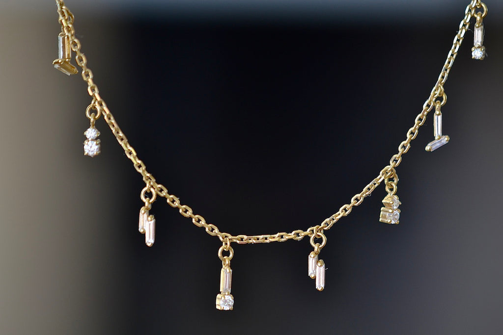 Close up of white diamond baguettes and round diamonds on Suzanne Kalan mini dangle necklace.