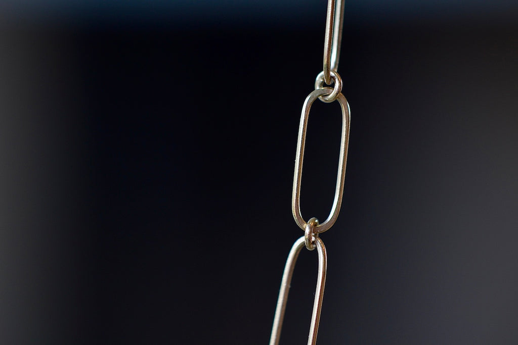 Close up of short flat clip on Kaylin Hertel's mixed paperclip chain necklace in 14k yellow gold. 