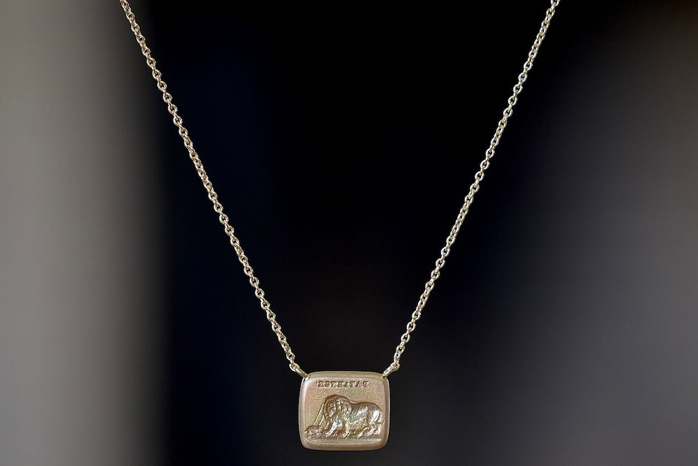 Lion and Mouse Duo Motto Necklace in 18k gold is a rectangular disc in gold with satin finish that will turn shiny over time features an image from the Aesop Fable ‘The Lion and the Mouse featuring the words 'patience". Made by stamping an 1800s carved seal with 'mottos' in French, Italian, Latin or English on to gold. 