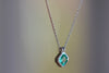 Side view of the The duo bale emerald pendant in platinum by Elizabeth Street is a bezel set Colombian emerald set on its axis in a double bale and on a platinum chain.