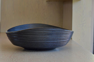 Side view of large Circle Factory bowl in black oak with ridges.