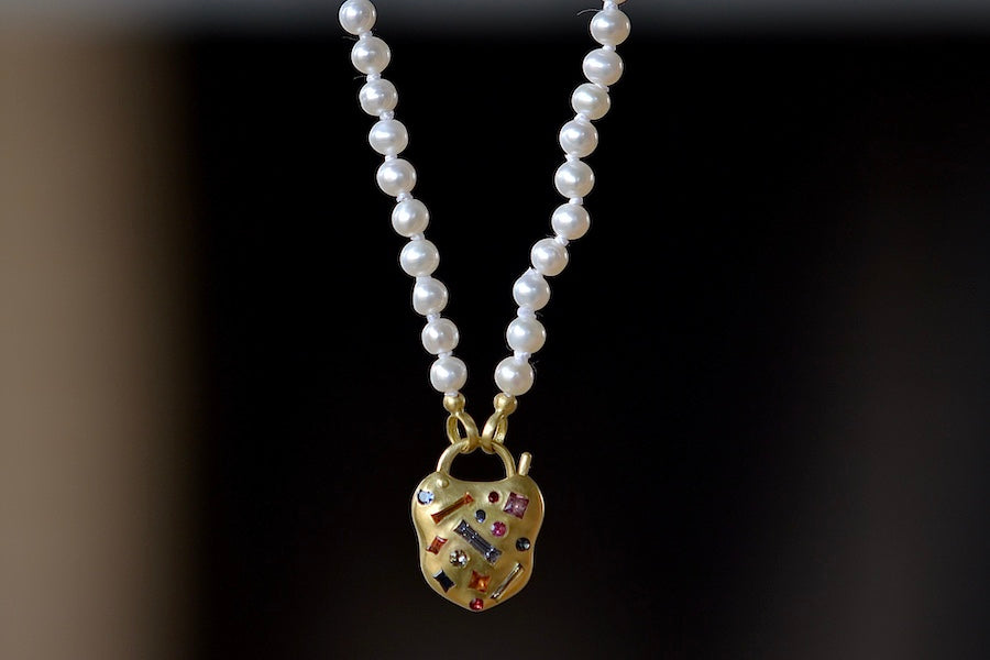 Polly Wales' Small Harlequin Coeur de Confetti Padlock Necklace shown on strand of fresh water pearls.