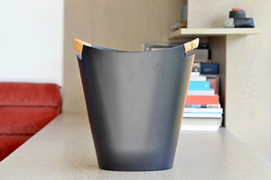 The Ørskov Wastebasket is made in matte black steel with cane wrapped handles and is 13" tall. It was designed by Grethe Kornerup-Bang in Denmark and is still  produced by Torben Orskow.