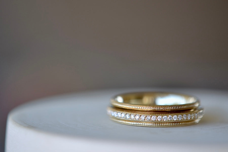 White Diamond Spinner Eternity Band by Elizabeth Street Jewelry is a spin on a classic! A white diamond eternity band with milgrain detail sits within a wider comfort fit gold band with rounded edges, allowing the eternity band to spin when touched. Handmade in Los Angeles.