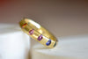 Celeste Ring in Blossom Crush by Polly Wales is a wide 18k recycled yellow gold band with sparkly rainbow sapphires in orange, yellow, green, pink, blue and purple peppered around the circumference. Recycled gold. Cast in Place. Cast not set. Handmade in Los Angeles.