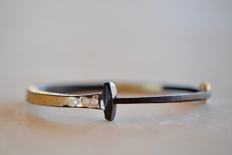 Three Stone Half and Half Nail Bracelet by Pat Flynn is a Forged nail bracelet with half-coverage in 22k fused gold with three (3) accent diamonds and completed with an 18k gold hinge and ball catch closure. Handcrafted in New York.