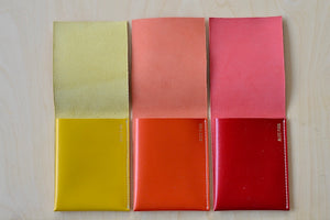 Yellow, orange and red with white stitching flap wallets by Alice Park shown open.