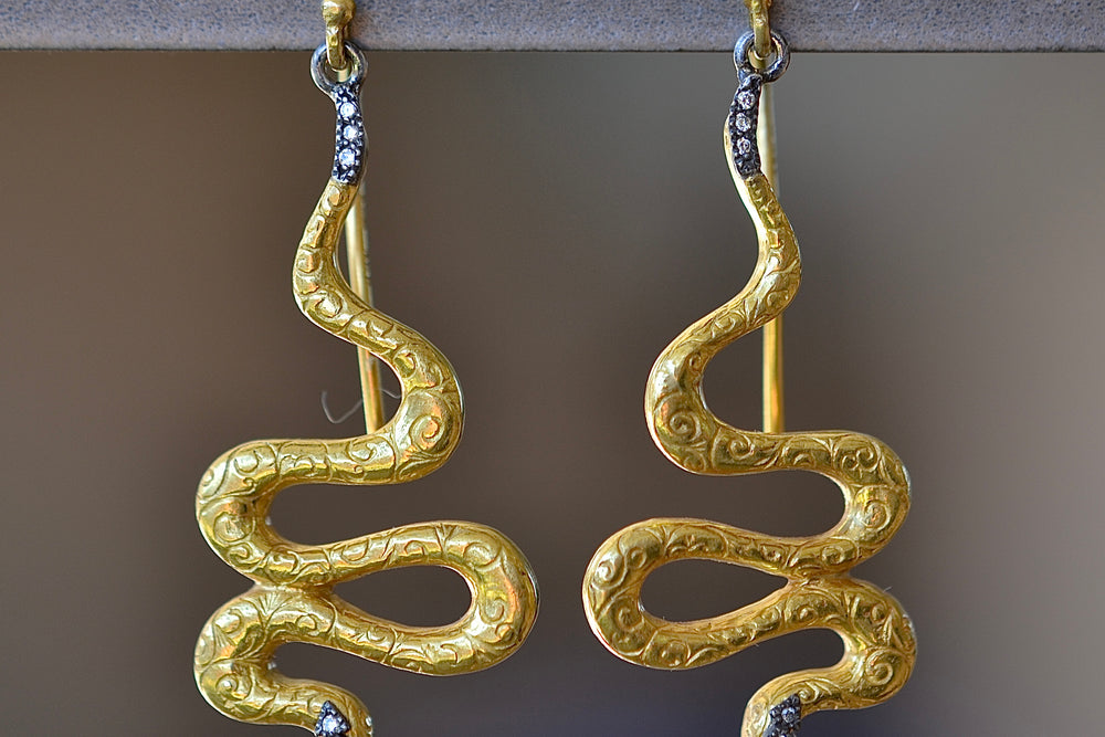 Detail of Snake Drop Earrings by Arman Sarkyssian are 22k gold snakes with oxidized sterling silver details, accent  pavé diamonds and engraved details on earring hooks. 