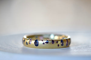 Alternate view of the Purple and Blue Sapphire Band Ring by Polly Wales is a narrow 18k yellow gold band with speckled purple, pink, blue to navy and black sapphires around the circumference for a beautiful confetti-like appearance. Recycled gold. Cast not set. Size 7.