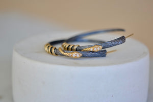 The Snake Hoop Earrings by Arman Sarkyssian on a stand..