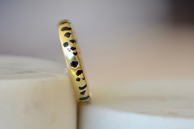 The Black Sapphire Confetti Band in size 8 designed by Polly Wales is a narrow 18k gold wedding band/ring speckled with black sapphires around the circumference. Cast not set. Made in Los Angeles. 