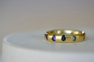 Celeste Ring in Blossom Crush by Polly Wales is a wide 18k recycled yellow gold band with sparkly rainbow sapphires in orange, yellow, green, pink, blue and purple peppered around the circumference. Recycled gold. Cast in Place. Cast not set. Handmade in Los Angeles.