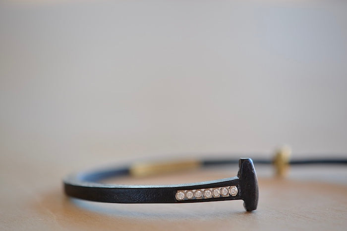 Pat Flynn Short Stripe Seven (7) Stone Bracelet is a Forged and tapered nail bracelet in blackened iron with seven accent diamonds on one side and completed with an 18k gold hinge and ball catch closure. Handcrafted in New York.