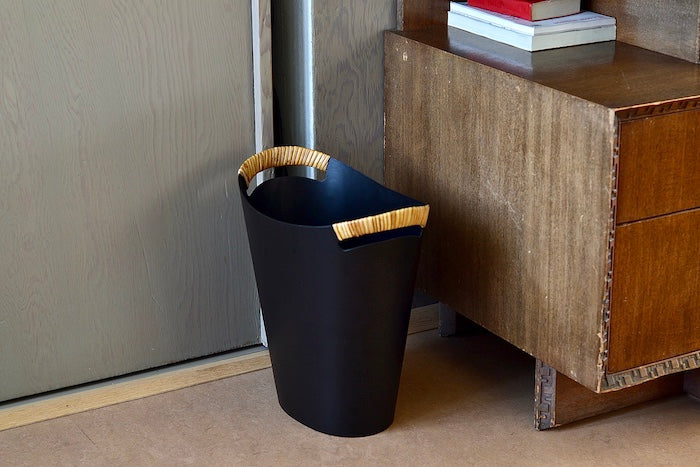 The Ørskov Wastebasket is made in matte black steel with cane wrapped handles and is 13" tall. It was designed by Grethe Kornerup-Bang in Denmark and is still  produced by Torben Orskow. Scale.