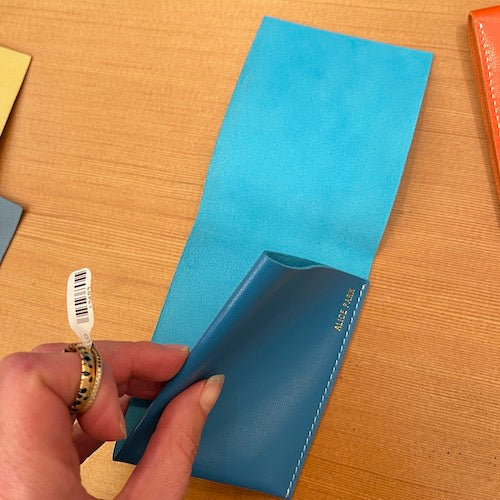 Simple Flap wallet in blue leather and white stitching from architect Alice Park shown empty..