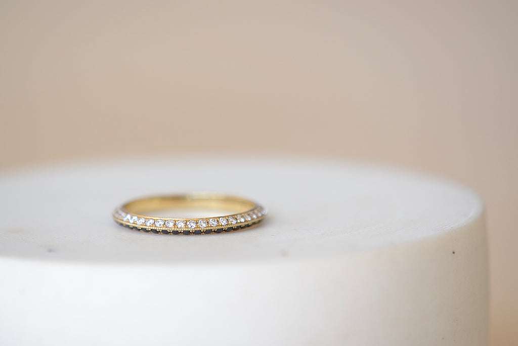 Lizzie Mandler The Othello Knife Edge Band ring by Lizzie Mandler is a wedding engagement band with White diamonds on one side and black round Diamond diamonds on the other in 18k yellow gold.