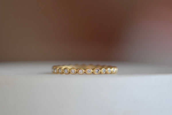 1mm thick porch band by Marian Maurer is a wedding band in bezel set round diamonds that is 1mm tall.