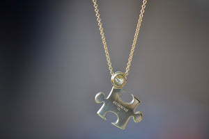 Mini Impetus Puzzle Piece Pendant by Retrouvai is a high polish puzzle piece in gold, accented with one white diamond hangs on a chain. Handcrafted in Los Angeles.